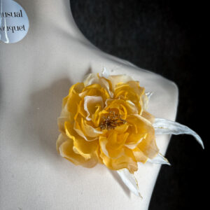 Spilla a forma di rosa in organza di seta color giallo goldfinch su manichino sartoriale.
