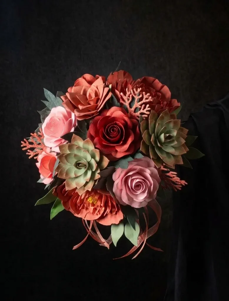 Bouquet di nozze corallo con rosa di colore corallo e rosa, peonie arancioni, piante grasse verdi e fogliame. Tutto realizzato a mano in carta da Jessica Ciaffarini