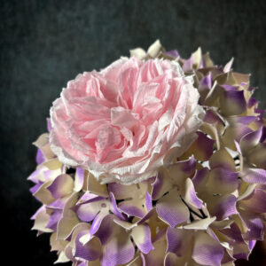 Primo piano ravvicinato dei petali realistici di una rosa inglese rosa in carta crespa pregiata all'interno di un bouquet da sposa.