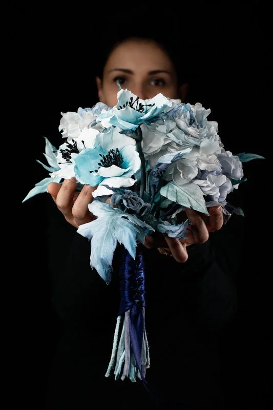 Ritratto dell'artista Jessica Ciaffarini che tiene in mano un bouquet artistico nei toni del bianco e del blu.